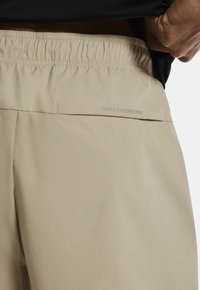 Beidīgas šorti ar elastīgu jostasvietu, ar tekstu "ŠVEICES INŽENIERIJA" gaiši pelēkā krāsā, gluda tekstūra un vienkāršs dizains.