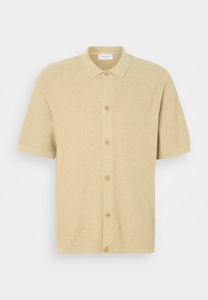Short-sleeve polo shirt in light beige, made of textured fabric. Features a button-up front and a classic collar.
