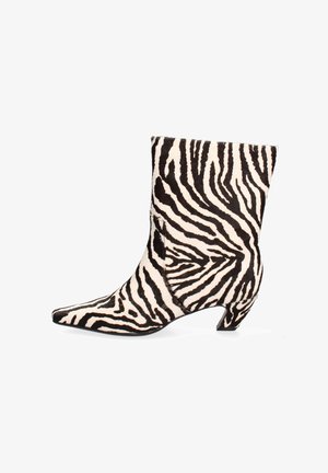 Zebra-muster Ankle Boot in Schwarz und Weiß. Hergestellt aus strukturiertem Material mit einer spitzen Zehe und einem niedrigen, gebogenen Absatz.