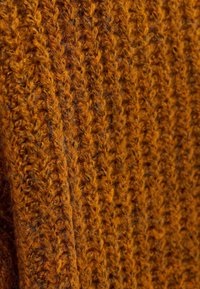 Strukturiertes Strickgewebe in einem kräftigen Orangeton, mit einem erhabenen Rippenmuster, sichtbaren Fasern und leichten Farbnuancen.