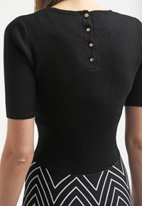 Zwarte fitted top met korte mouwen, ronde hals en vijfknopssluiting op de rug; gemaakt van een zachte, gestructureerde stof.