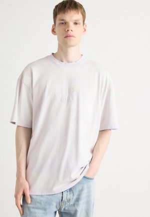 Light lavender oversized t-shirt made of cotton, featuring a subtle embroidered "HUGO" logo on the chest and short sleeves.