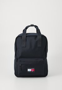 Svart ryggsäck i slitstarkt tyg, med två handtag upptill, en framfick med dragkedja och en liten logotyp i rött, vitt och blått.
