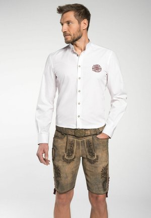 Weißes Hemd mit Kragen; besticktes Design auf der Brust. Braune Lederhosen mit floraler Stickerei und dekorativem Gürtel.