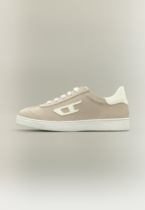 Baskets basses en daim beige avec lacets blancs, logo blanc sur le côté, semelle blanche et col de talon rembourré blanc sur fond neutre.