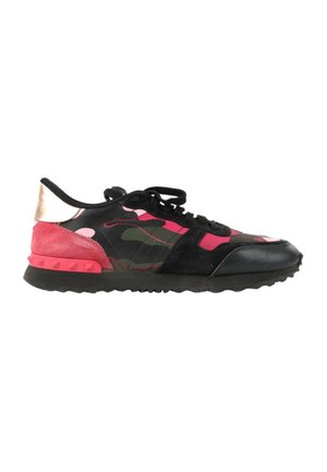 Baskets basses avec semelle noire, motif camouflage noir et rose, talon en daim rouge et lacets noirs sur fond blanc.