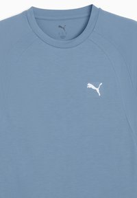 Lyseblå kortærmet t-shirt lavet af blødt stof med rund halsudskæring og raglanærmer. Har et hvidt Puma-logo på brystet.