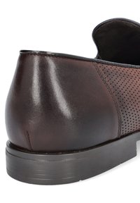 Brązowy skórzany but o gładkim wykończeniu i perforowanych akcentach. Posiada niski profil, zaokrąglony obcas oraz teksturowaną gumową podeszwę.