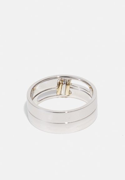 Iring dual-band din argint cu un finisaj neted, accentuat de aur și cu un design deschis, subliniind o formă geometrică contemporană.