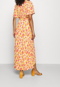 Maxiklänning i mönster med blommor i rosa, gult och vitt. Korta ärmar, insvängd midja, fladdrande kjol. Matchad med orange blockklacksandaler.