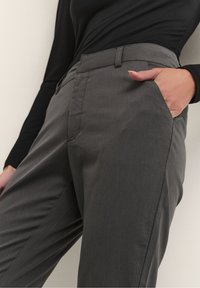I pantaloni grigi su misura presentano una texture liscia, una parte frontale piatta, tasche laterali e una vestibilità dritta. La vita è dotata di passanti per la cintura.