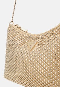 Borsa beige con superficie testurizzata decorata con strass argentati; presenta un logo triangolare dorato e una tracolla a catena.