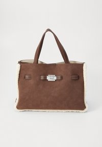 Sac fourre-tout en suède marron avec des bordures en fausse fourrure crème douce, doubles poignées et un fermoir rectangulaire en argent sur fond blanc uni.