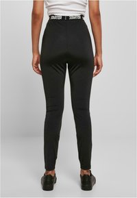 Fekete leggings rugalmas anyagból, magas derékpánttal és "STARTER" logóval. Simaság jellemzi, testhezálló kialakítás és szűkülő szárak.