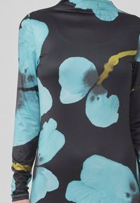 Robe à manches longues en tissu noir avec de grands motifs floraux turquoise rehaussés de détails jaunes. Texture lisse et coupe ajustée.