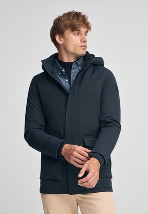 Donkerblauwe hoodiejacket met een gestructureerd oppervlak, ritssluiting aan de voorkant en zijzakken. Draag het over een denimbloes, met ribgebreide manchetten.