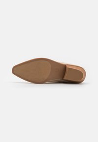 Beige suède enkelboot met een gladde oppervlakte, spitse neus, stevige tan rubberen zool en een gestructureerd grip-patroon. Maatlabel 6.5 zichtbaar.