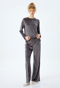 Grå velour pyjamas-set med lång ärm, dragsko i midjan och spridda ljusa accenter. Mjuk textur och avslappnad passform.
