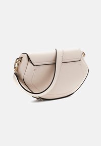 Borsa a mano in pelle beige con forma curvata, bordi neri, tracolla regolabile e dettagli in oro. Presenta finiture di cucitura minimalista.