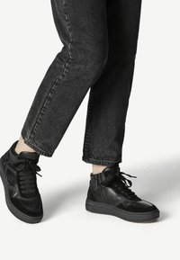 Höga svarta sneakers med en blandning av läder och mocka, strukturerad yta, runda snören och en vadderad krage för stöd.