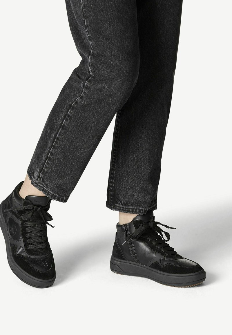 Höga svarta sneakers med en blandning av läder och mocka, strukturerad yta, runda snören och en vadderad krage för stöd.