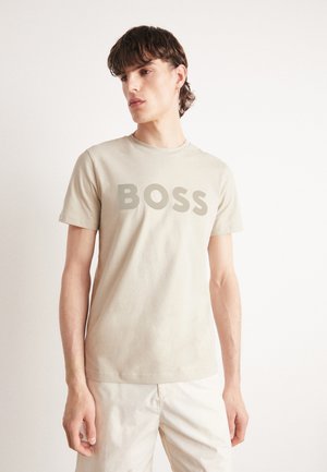 Beige short-sleeve t-shirt made of cotton, featuring a prominent gray "BOSS" logo on the front, with a crew neckline and a relaxed fit.