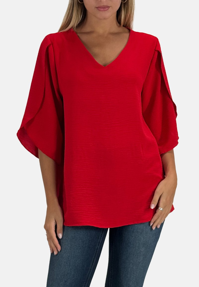 Top rosso con scollo a V ampio, maniche larghe e fluide e tessuto strutturato. Design a tinta unita, abbinato a jeans blu scuro.