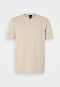 T-shirt beige à manches courtes en coton doux. Col rond avec étiquette de la marque à l'intérieur ; design simple, coupe droite et sans motifs visibles.