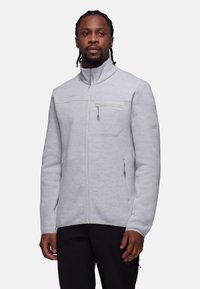 Giacca in pile grigia chiara con colletto alto, chiusura con zip, tasca sul petto e dettagli in contrasto. Ideale per attività all'aperto.