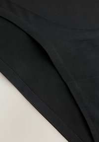 Czarna tkanina, gładka tekstura, fałdy nakładające się w warstwowym wzorze. Miękki, elastyczny materiał bez widocznych wzorów czy szczegółów sprzętowych.
