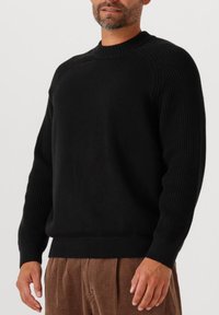 Maglione nero lavorato a maglia con texture a coste su maniche e scollatura, corpo solido e orlo aderente. Adatto per un look casual.
