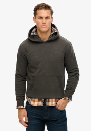 Hoodie in donkergrijze katoenen mix met een voorzak en textuuraccenten, gedragen over een geruite flanellen shirt.