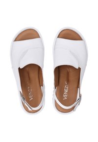 Weiße Leder-Sandalen mit offener Zehe, geschwungenem Oberdesign, braunem Fußbett und verstellbarem Riemen am Knöchel. Dezente Nähdetails.