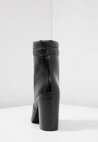 Stivale alla caviglia in pelle nera con punta arrotondata, collo imbottito e tacco a blocco. Presenta una linguetta sul retro e un dettagliato logo discreto.