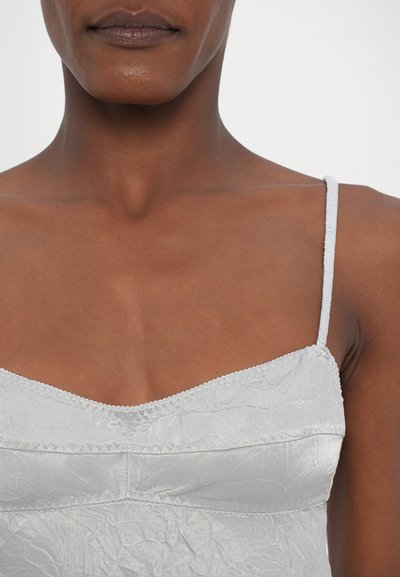 Camiseta de tirantes finos en gris claro, con un tejido texturizado, un delicado borde de encaje alrededor del escote y una silueta ajustada.