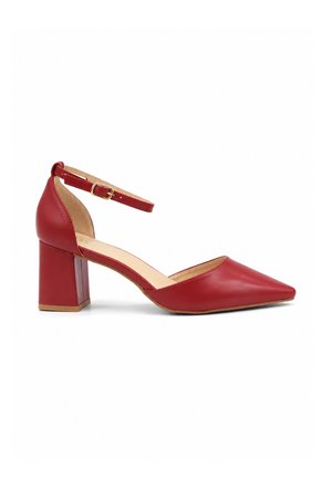 Roter Leder-Pumps mit spitzer Spitze, Blockabsatz und dünnem Knöchelriemen, der mit einer kleinen goldenen Schnalle auf weißem Hintergrund befestigt ist.