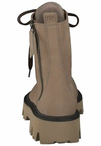 Stivale alla caviglia in pelle marrone chiaro con cerniera, punta rotonda e suola chunky beige. Presenta una finitura testurizzata e un linguetta per una facile calzata.
