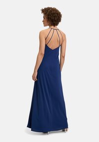 Robe maxi bleu marine avec un corsage ajusté, des fines bretelles et un dos décolleté. Fabriquée en tissu doux, elle présente un léger tombé et une fermeture éclair.