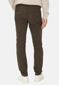 Bruine stretchstof jeans met een slim fit, voorzien van twee achterzakken en subtiele textuur, gecombineerd met witte sneakers.