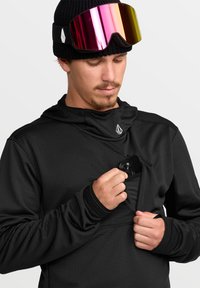 Haut à capuche noir à manches longues avec un tissu texturé et un design à enfiler. Comprend une poche avant pour le stockage et un logo sur la poitrine.