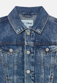 Veste en denim avec un col classique, une fermeture à boutons, deux poches poitrine et un léger effet usé. Couleur bleu clair avec des coutures contrastées.