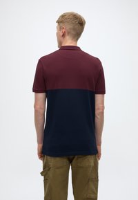 Maroon and navy polo shirt, short sleeves, collar, smooth texture. Pairing with cargo pants in a light brown shade.
