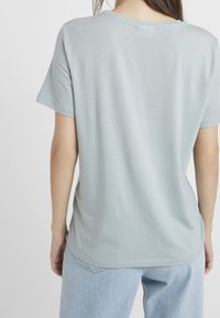 Světlomodré tričko s krátkým rukávem z měkké tkaniny, s kulatým výstřihem a volným střihem. Hladký povrch a minimalistický design bez viditelných vzorů.