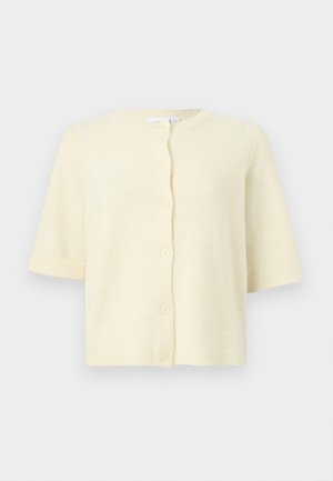 Kermanvärinen lyhythihainen neuletakki pyöreällä pääntiellä ja viidellä edessä olevalla napilla, esillä yksinkertaisella vaalealla taustalla.