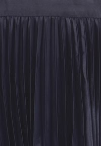 Námořnická plisovaná tkanina s hladkým leskem, zdobená vertikálními pruhy, vytvářející texturovaný vzhled ideální pro formální oblečení.