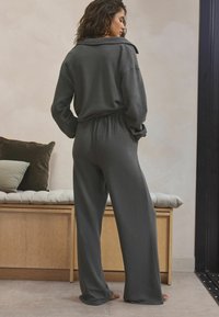 Gray lounge set with a collared top and wide-leg pants. Material appears soft, with a textured finish. Features elastic waistband.