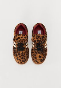 Sneakers i leopardprint med en overdel i brun ruskind, sorte snørebånd og hvide striber på siderne. Polstret indvendig i rød. Rund tådesign.
