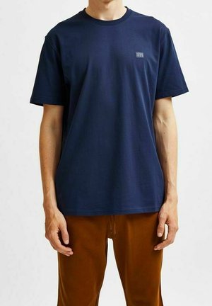 T-shirt en coton bleu marine à manches courtes, col rond et petit logo sur le côté gauche de la poitrine. Design simple et coupe décontractée.