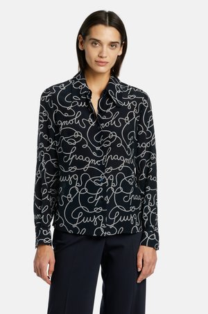 Long-sleeve black blouse with white script pattern. Features a collared neckline and buttons on the front. Soft fabric with a smooth texture.