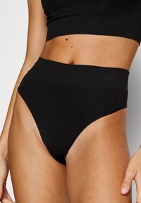 High-waisted black underwear made of smooth material with a stretchy waistband. Features minimal stitching and a sleek design.